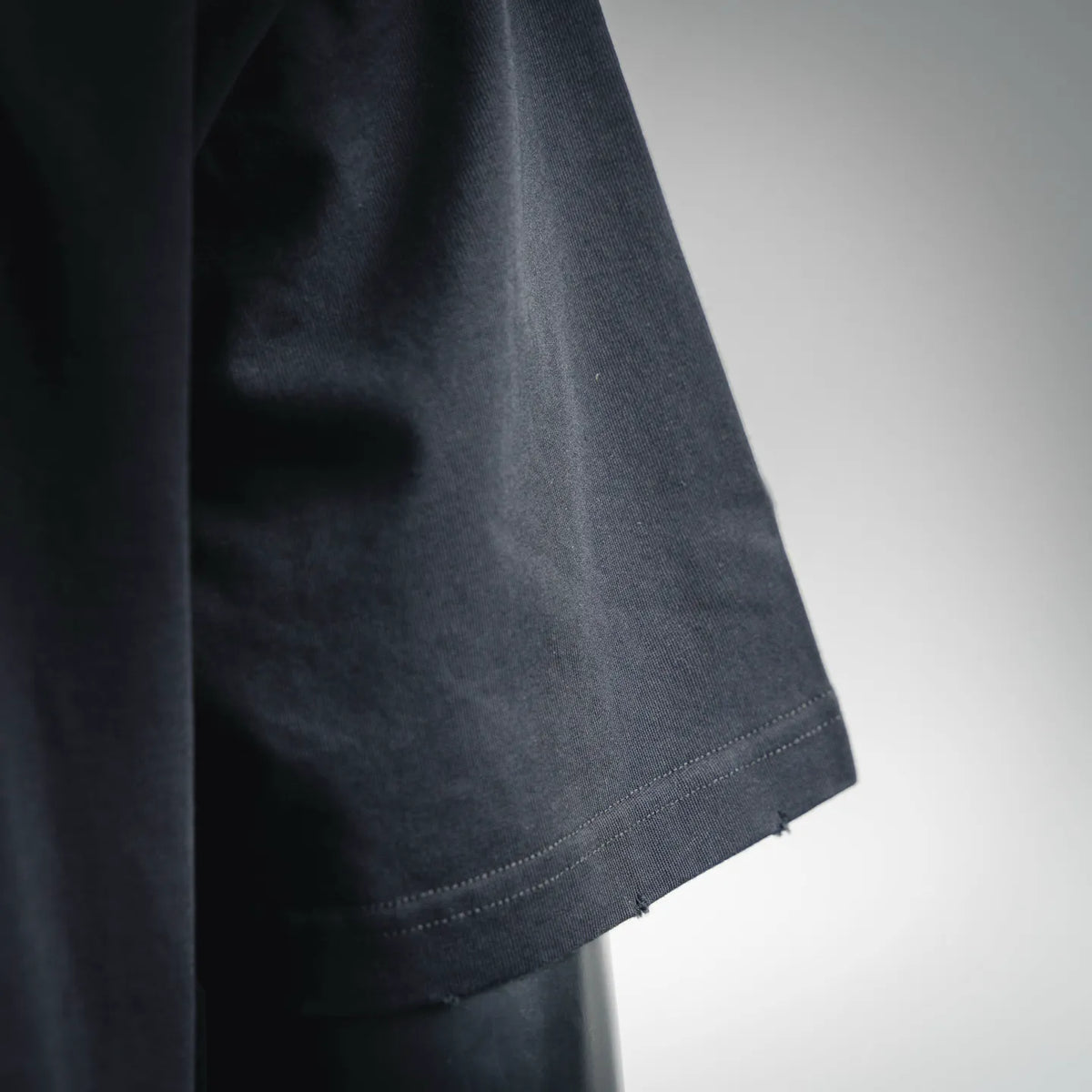 Close-up of black short-sleeve T-shirt sleeve edge and stitching.