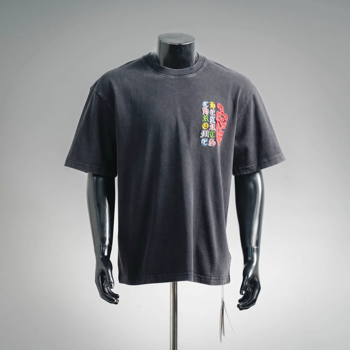 Dark charcoal crew-neck t-shirt with small multicolor embroidered chest graphic.