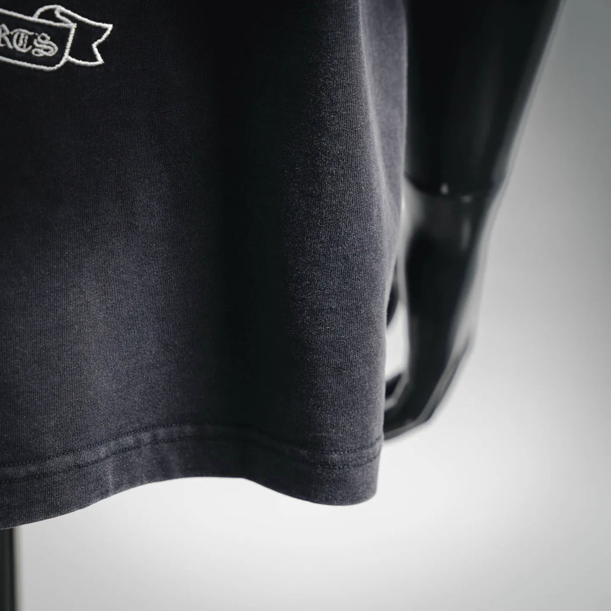 Dark charcoal t-shirt sleeve and curved hem detail.