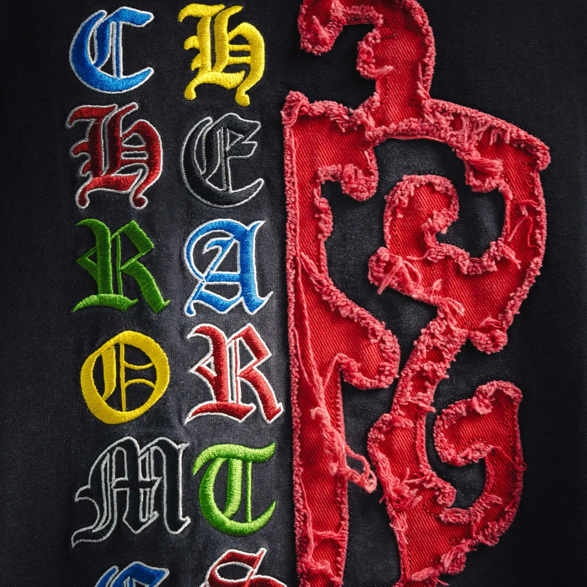 Embroidered front graphic with multicolor letters and red heart on dark t-shirt.
