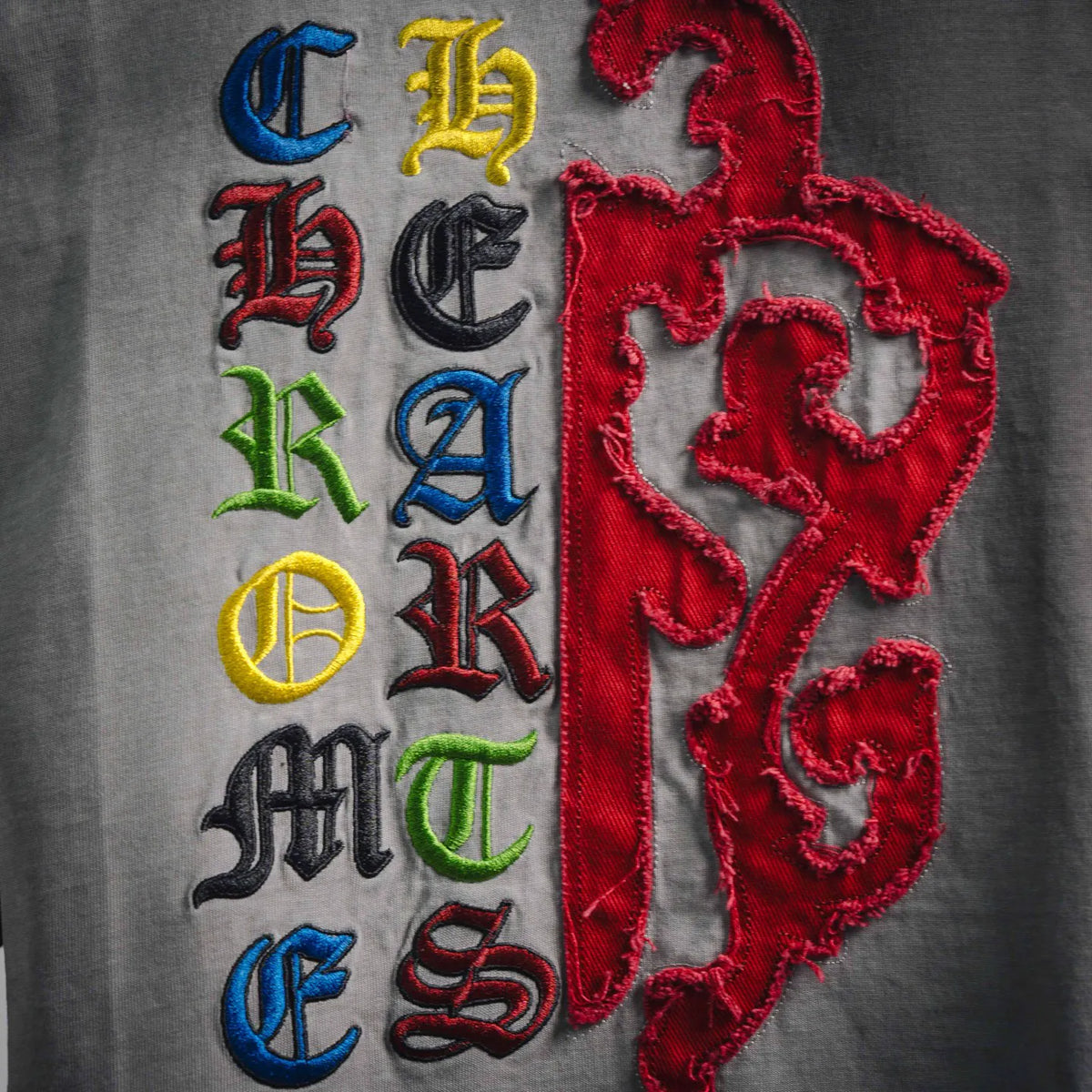 Close-up of gray T-shirt embroidery with red graphic and colorful letter details