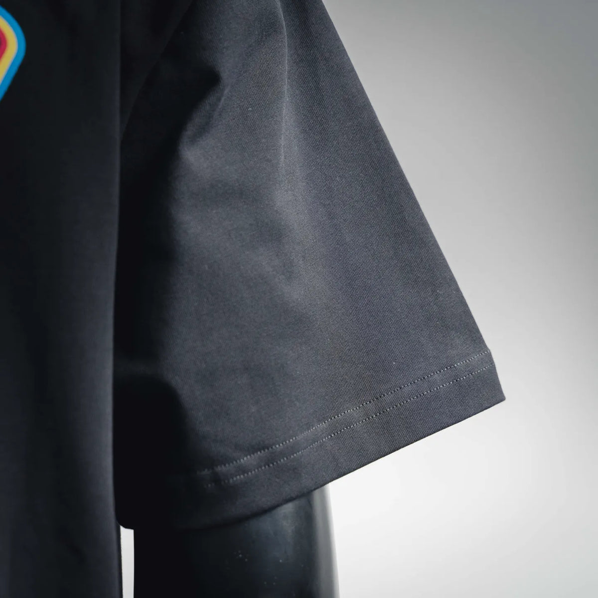 Black T-shirt sleeve and hem with visible stitching along the bottom edge
