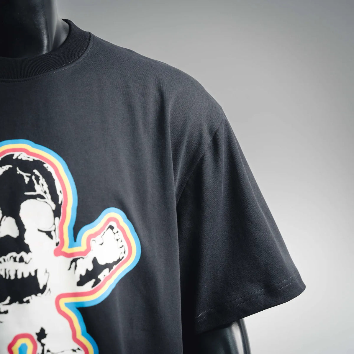 Black T-shirt front close-up showing partial skull-and-rainbow heart graphic