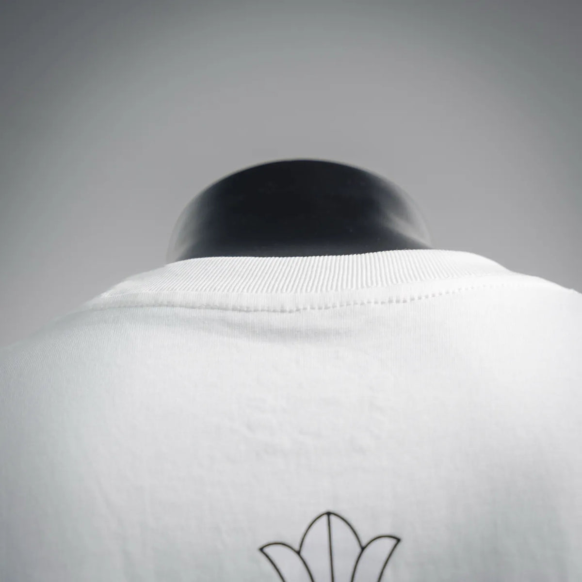 White short-sleeve T-shirt with embroidered flower design at back neckline.