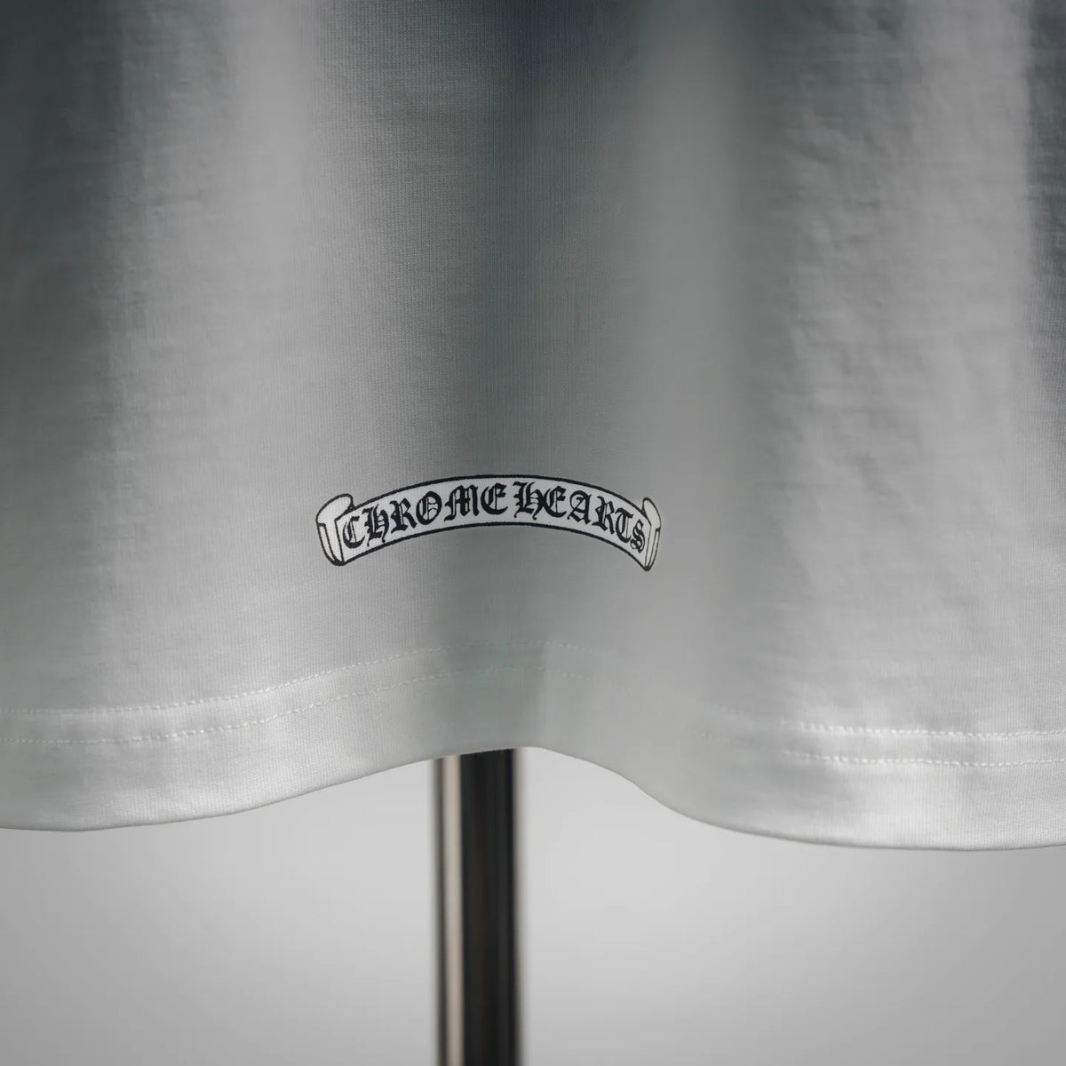 White short-sleeve T-shirt with “Chrome Hearts” logo on lower front hem.