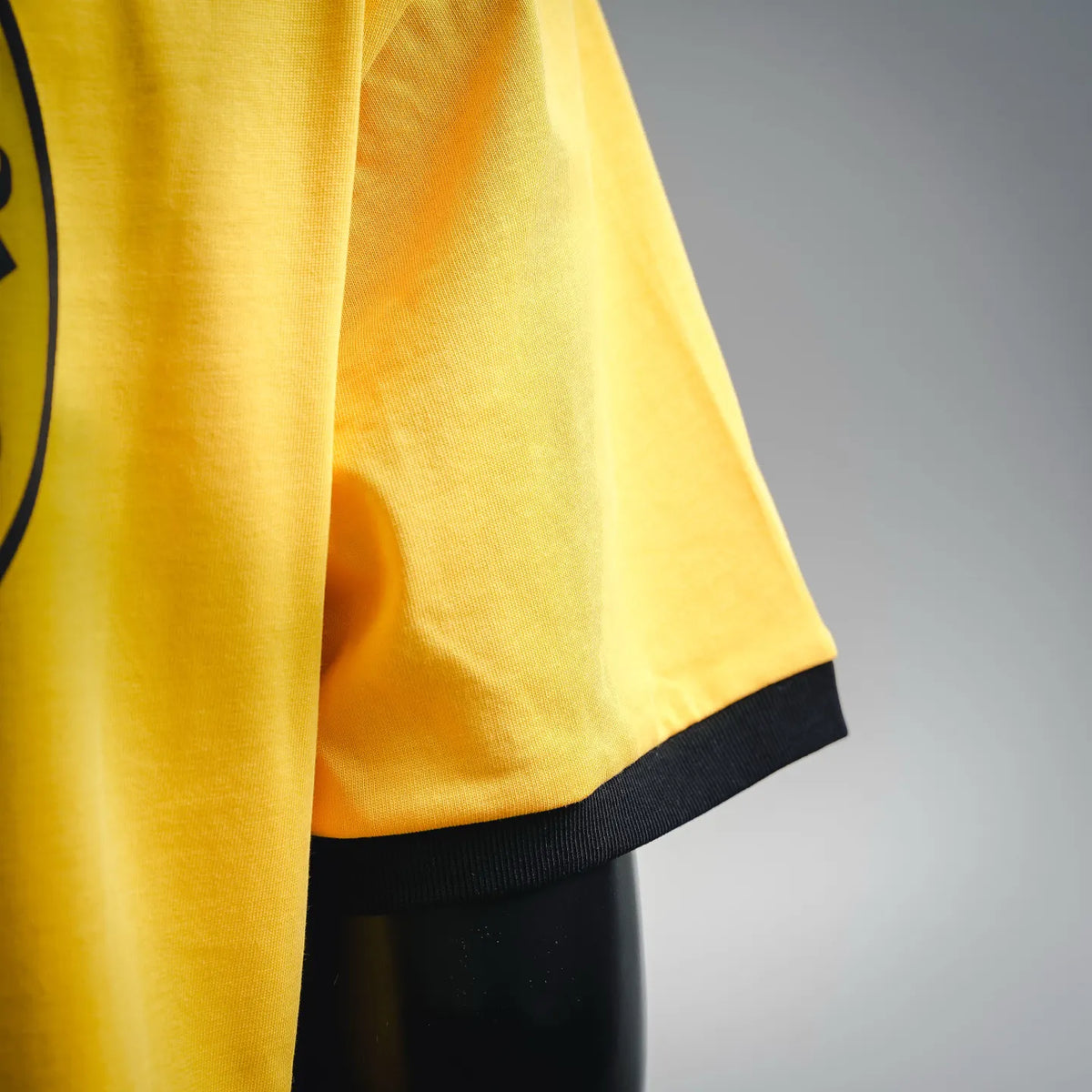 Yellow T-shirt side view with black hem trim and smooth short sleeves