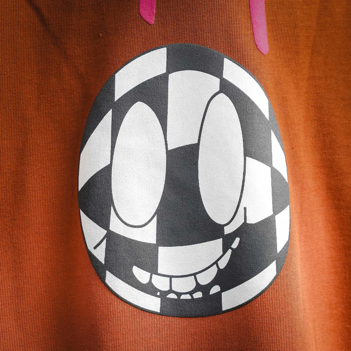 Close-up of orange T-shirt front graphic: smiling checker ball