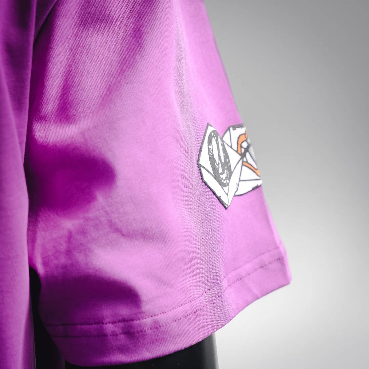 Purple T-shirt with side sleeve graphic patch near hem