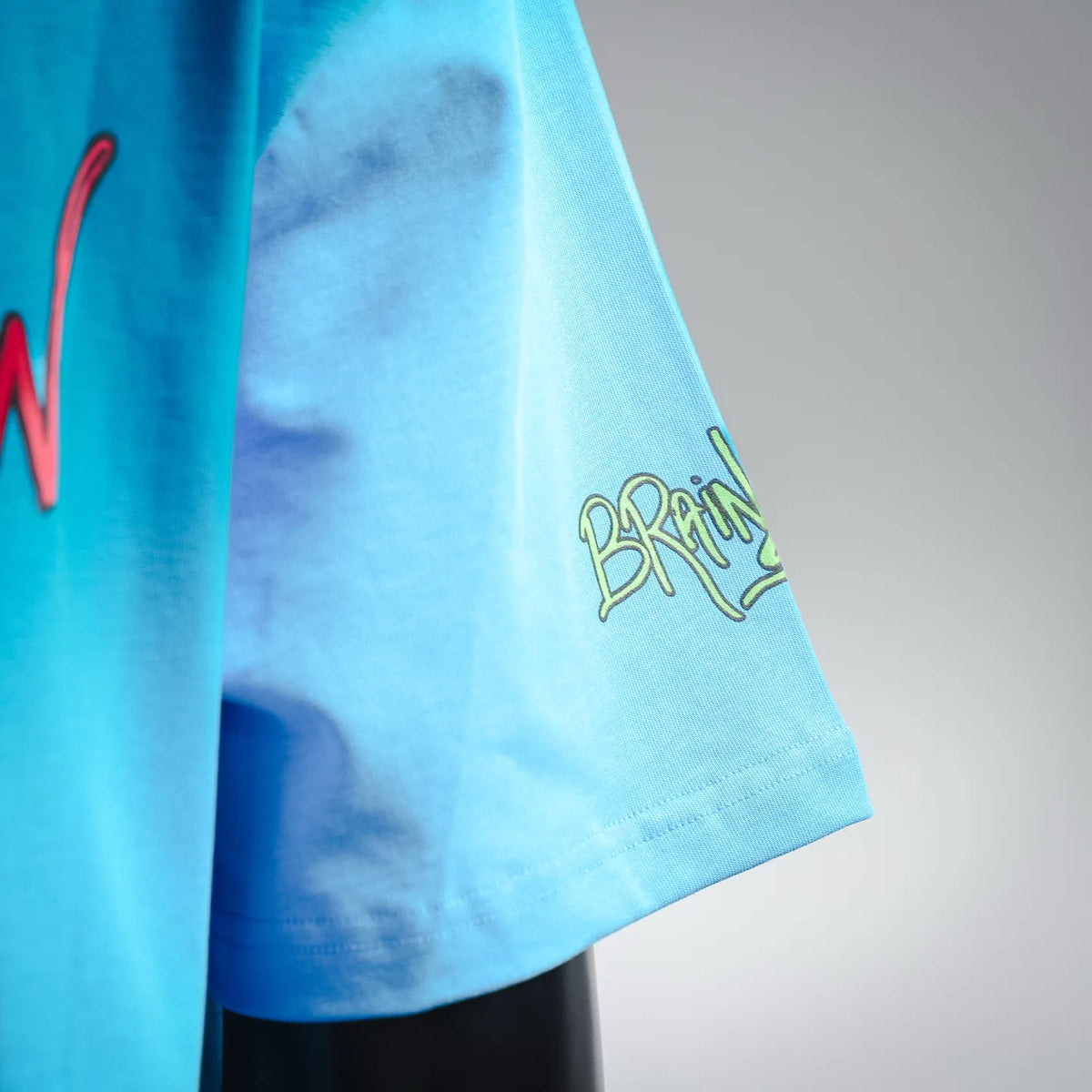 Light blue T-shirt sleeve hem with small green BRAIN graphic