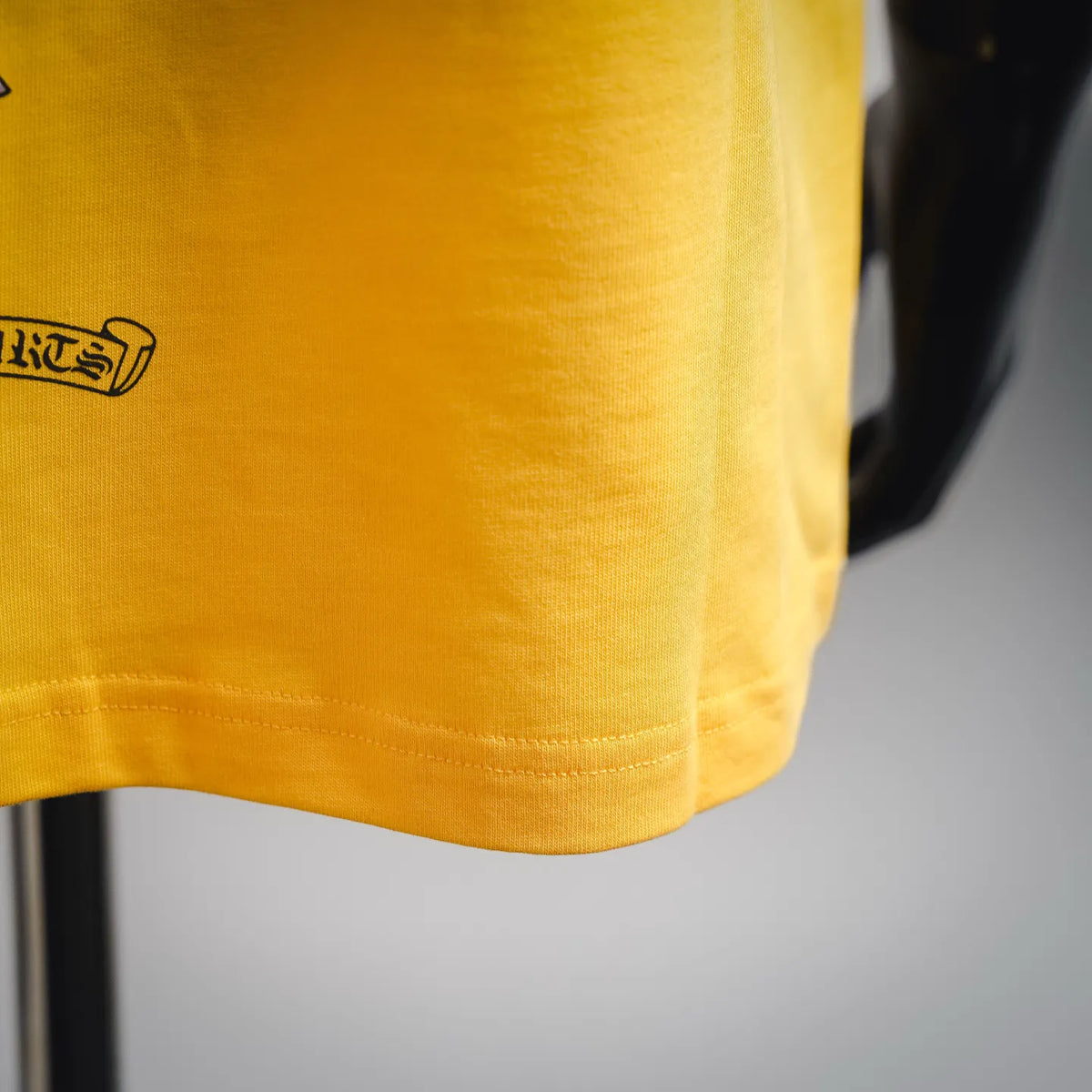 Close-up of yellow T-shirt hem with stitched bottom and curved seam