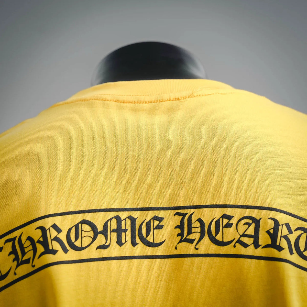 Close-up of yellow T-shirt back graphic band with large gothic-style lettering