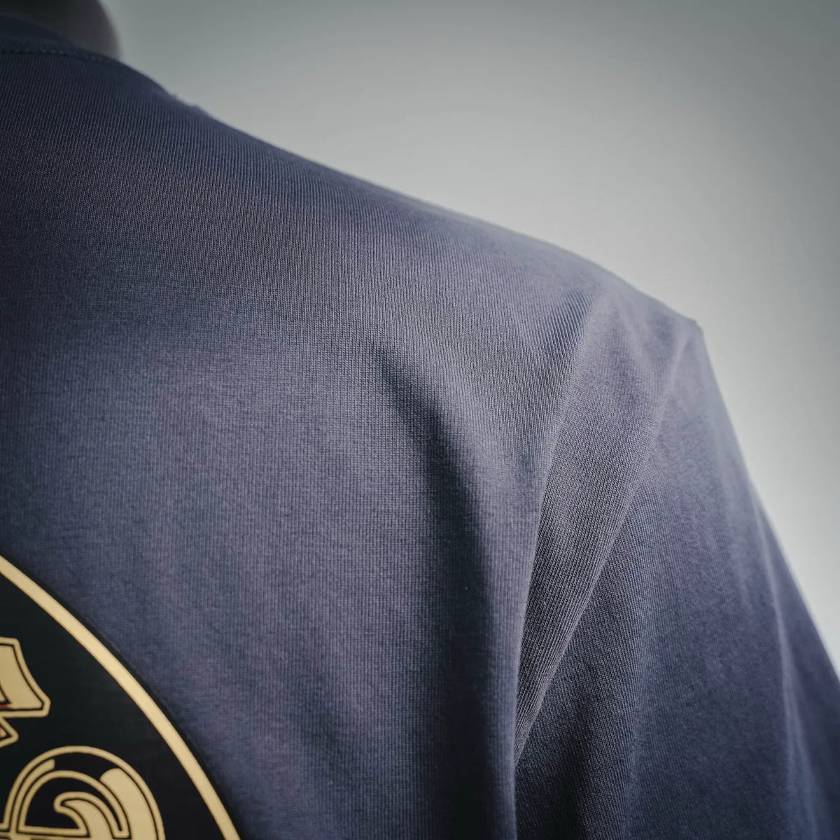 Close-up of dark navy T-shirt fabric with part of the circular back graphic at shoulder