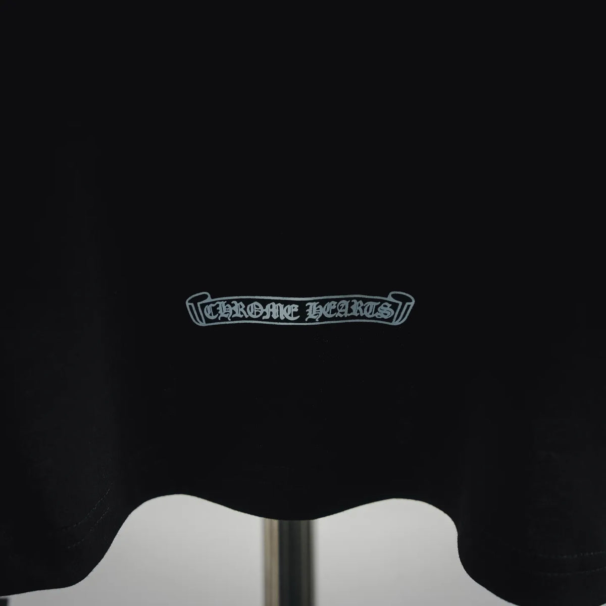 Black T-shirt chest area with small embroidered-style logo text patch