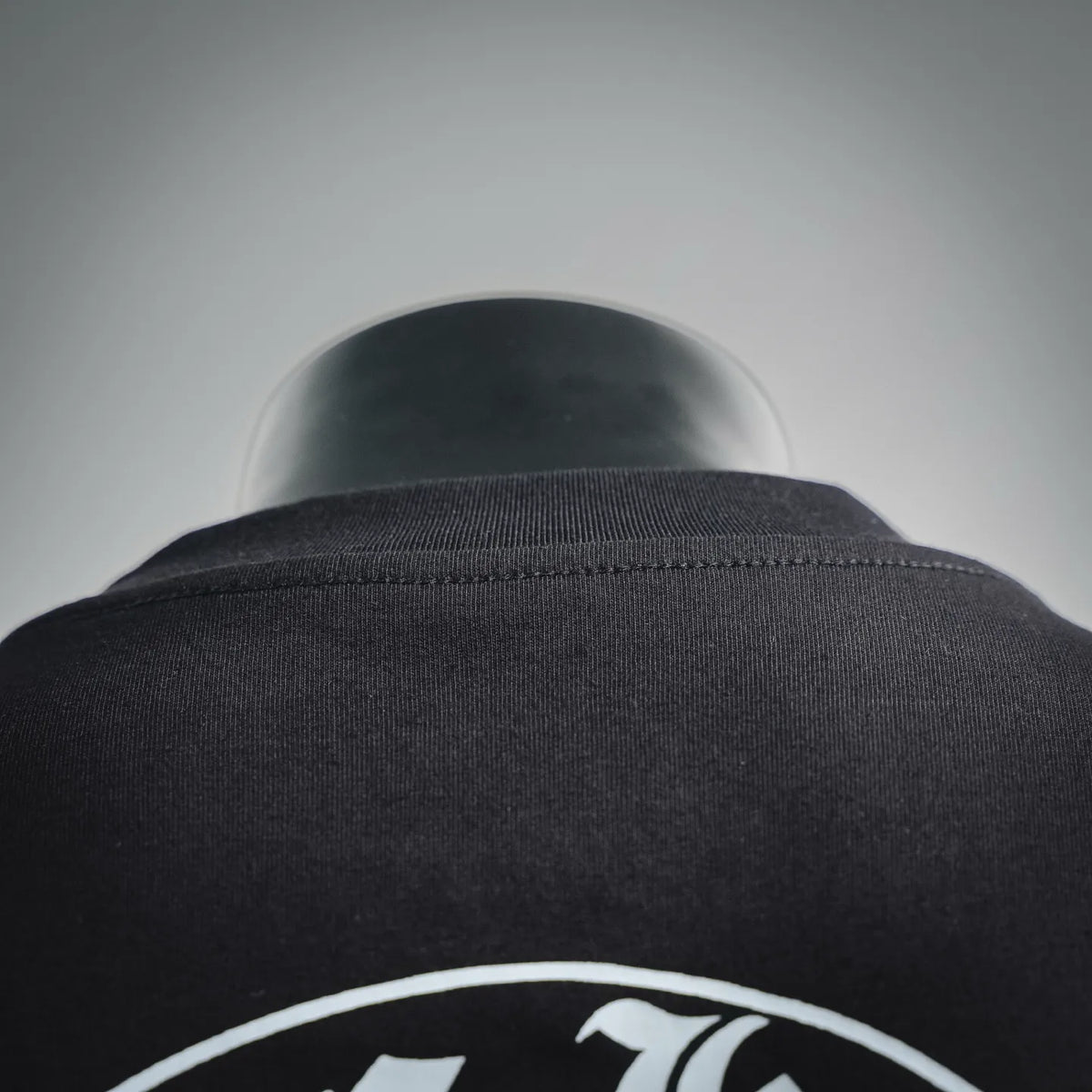 Black T-shirt back neck close-up with collar stitching and fabric texture