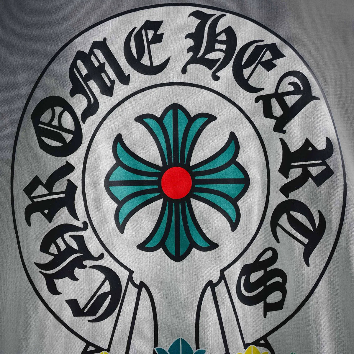 Close-up of circular black-and-teal emblem graphic on white T-shirt