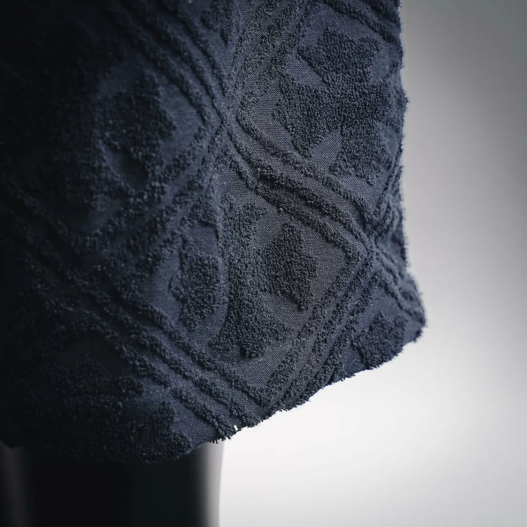 Close-up of textured dark navy shorts fabric with raised pattern