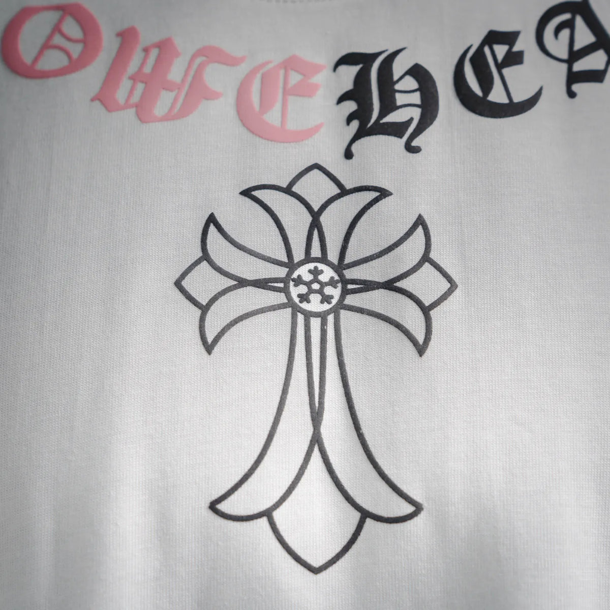 Close-up of white T-shirt front cross graphic with pink and black lettering