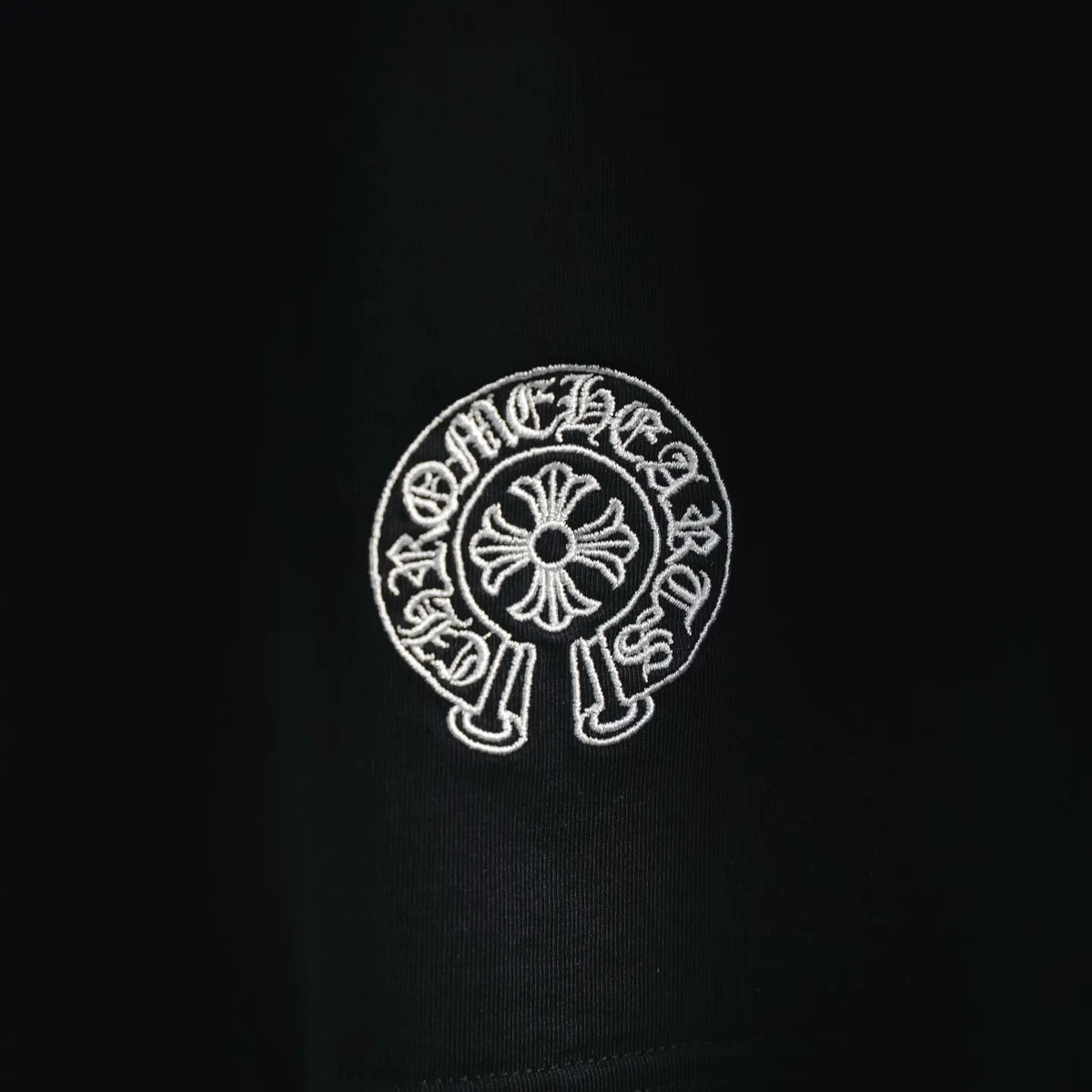 Close-up of embroidered circular emblem on black T-shirt chest
