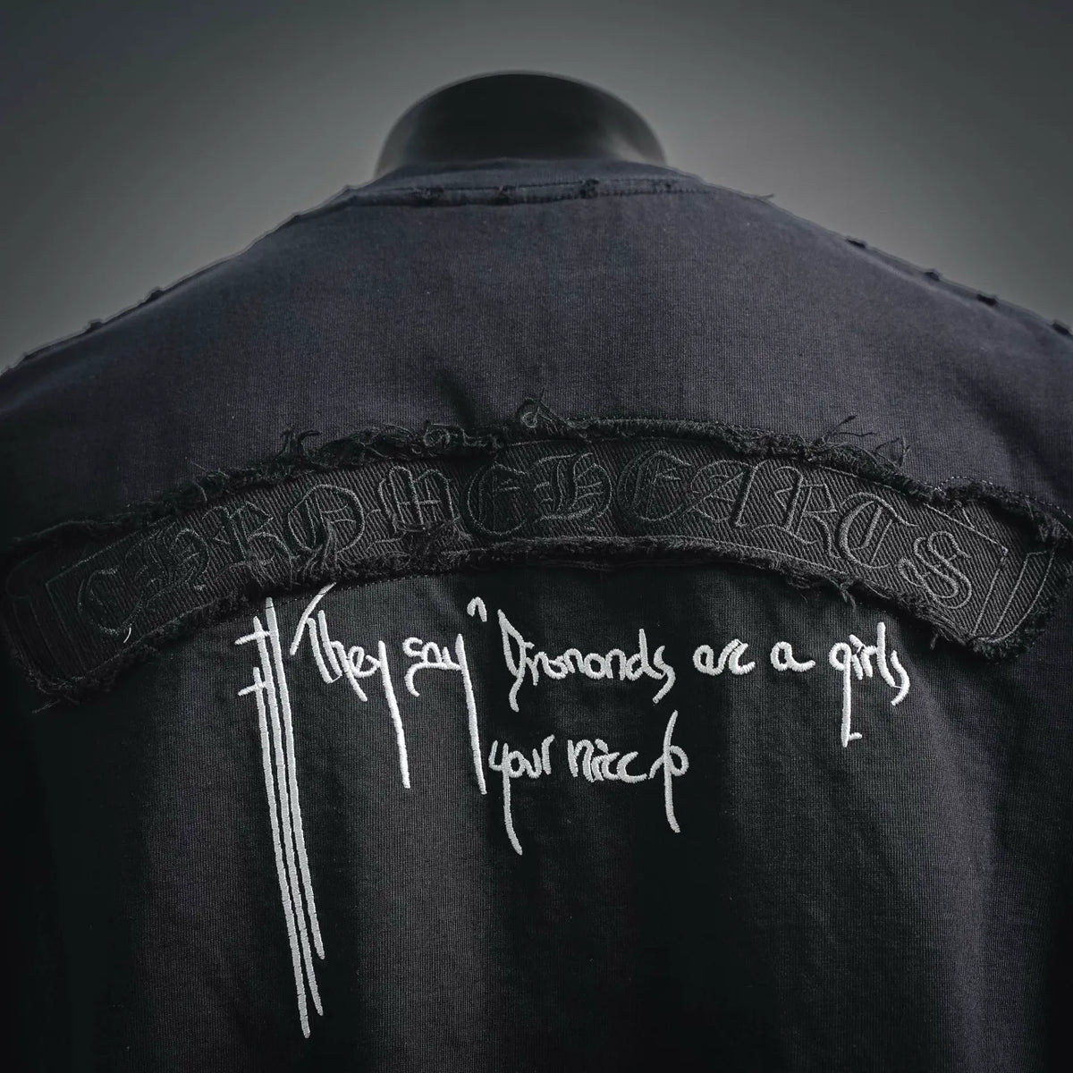 Close-up of embroidered back graphic with white script and decorative cross icons