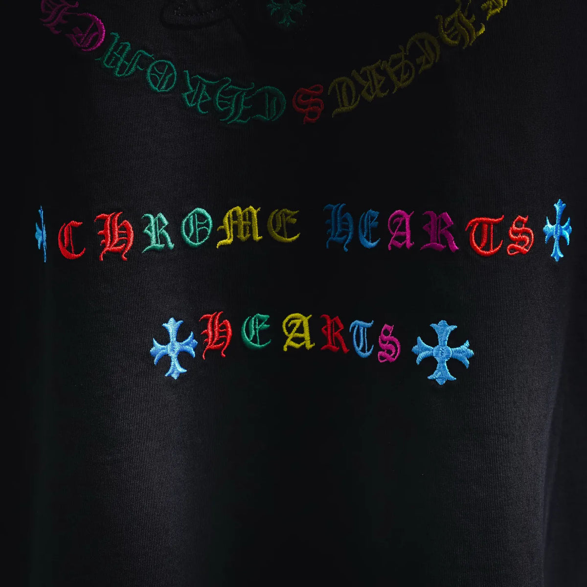 Close-up of multicolor gothic-style logo text on a black T-shirt.