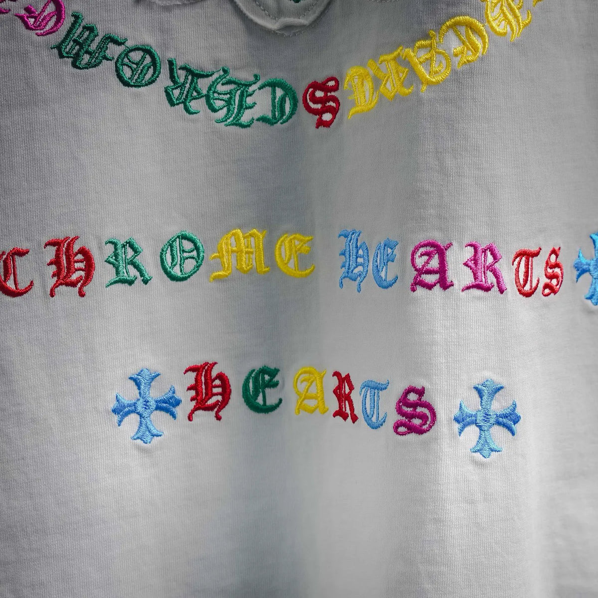 Close-up of colorful embroidered-style text on a white T-shirt