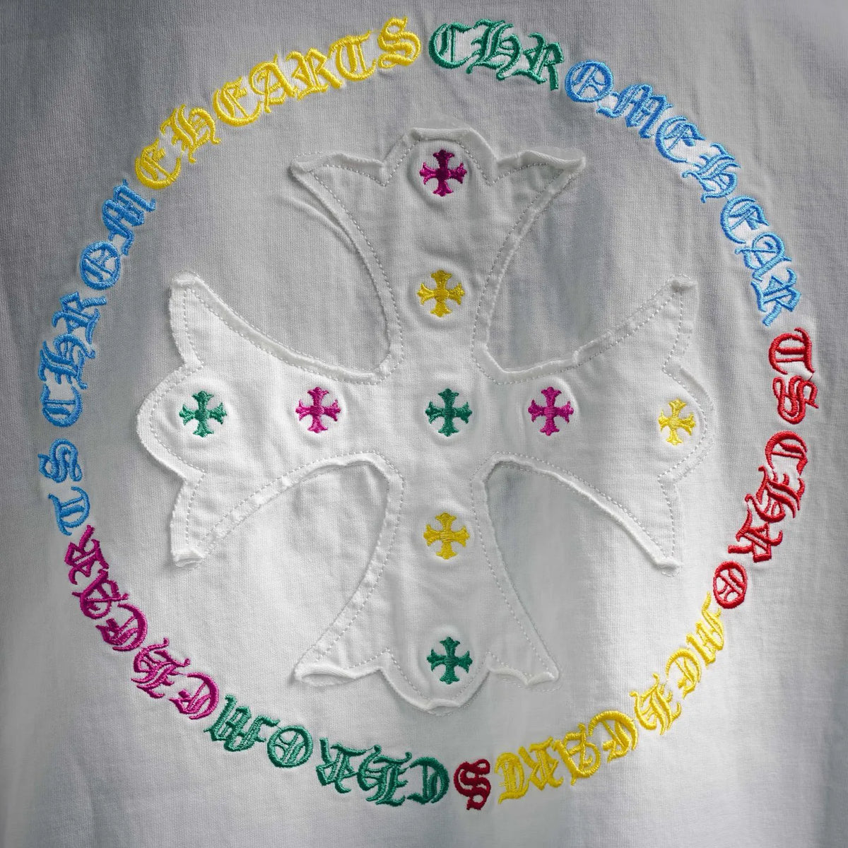 Close-up of colorful starburst emblem with cross symbols on white T-shirt