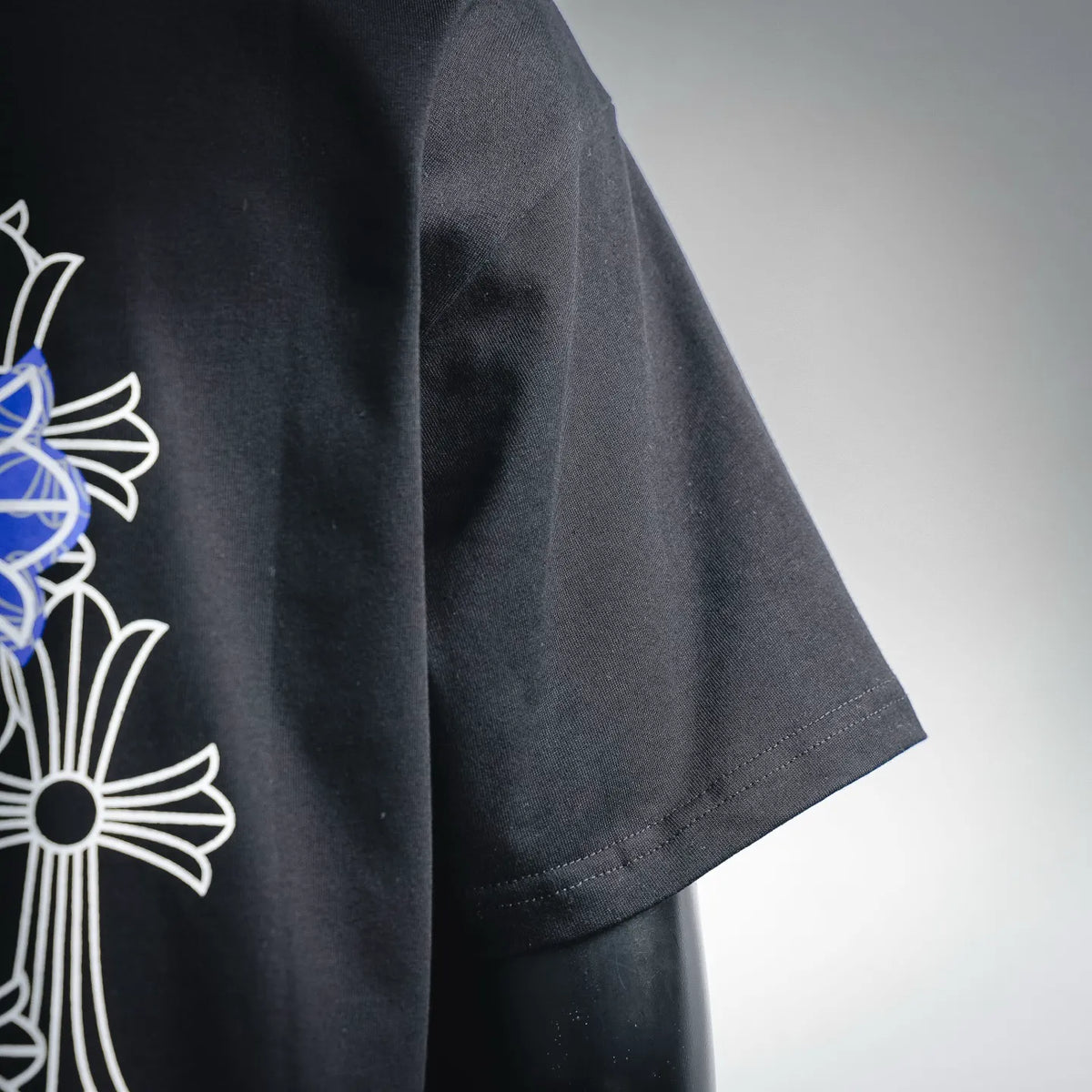 Black short-sleeve T-shirt sleeve with partial blue-and-white cross graphic