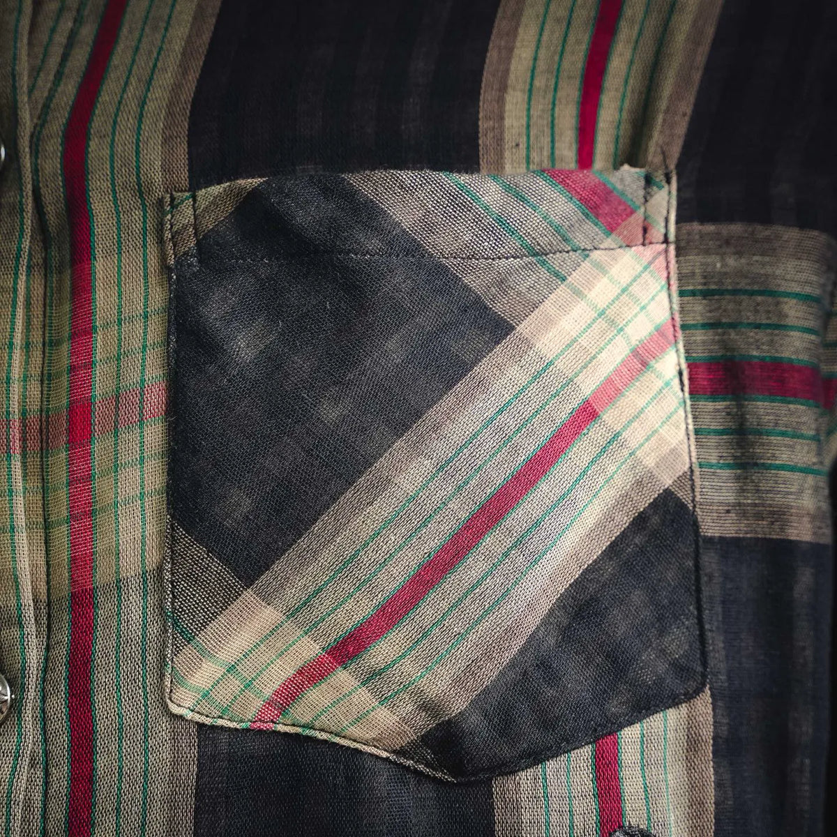 Chest pocket on plaid long-sleeve shirt with diagonal stripe patch and dark background