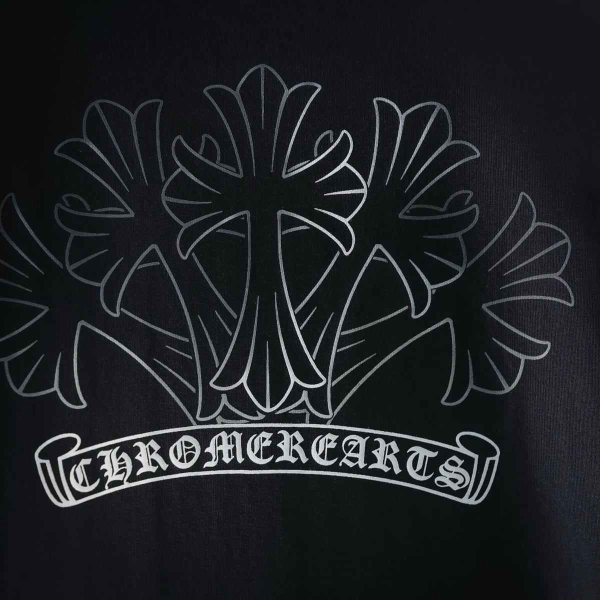 Close-up of white back graphic text and floral cross on T-shirt