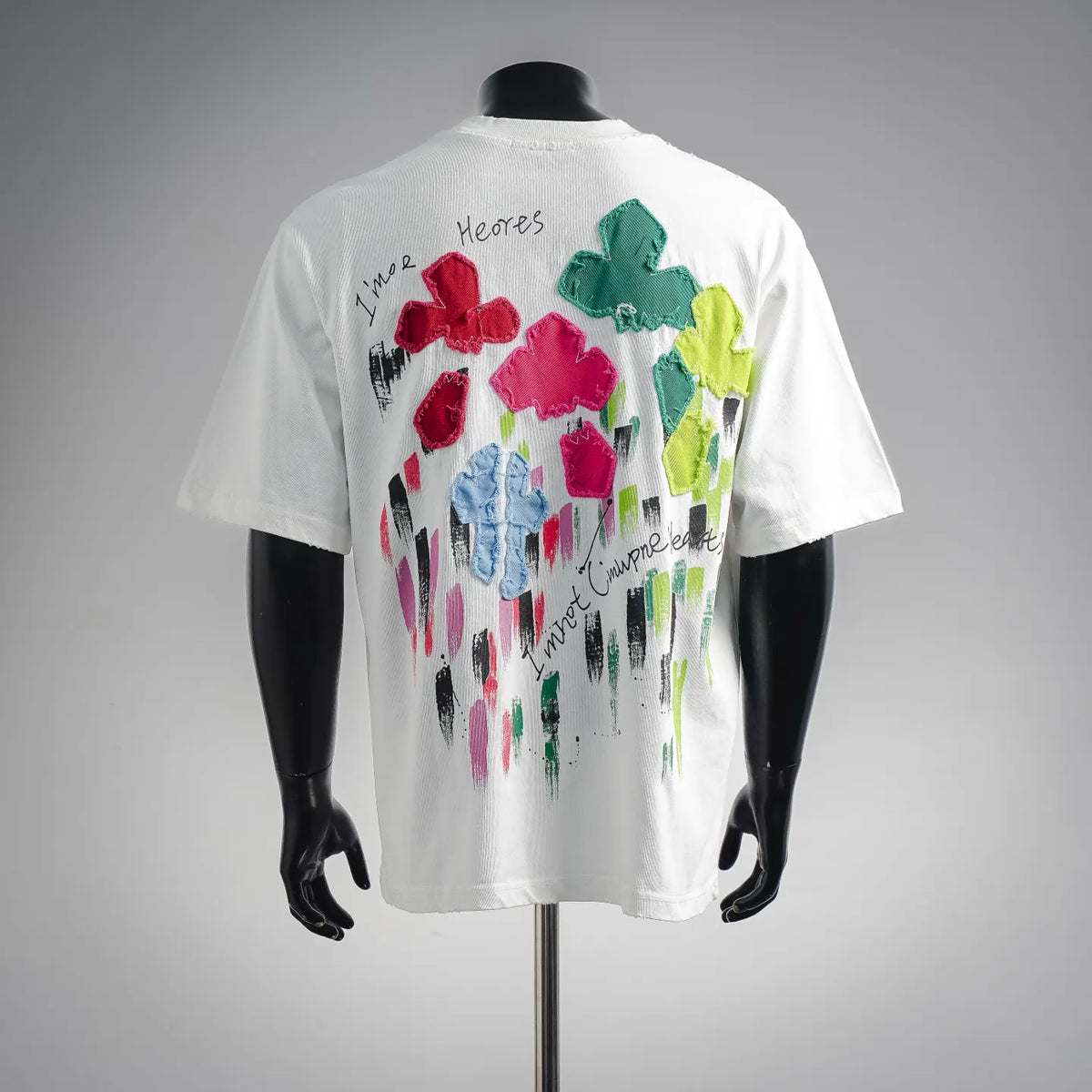 White T-shirt back with multicolor flower patches and paint-stroke cursive text