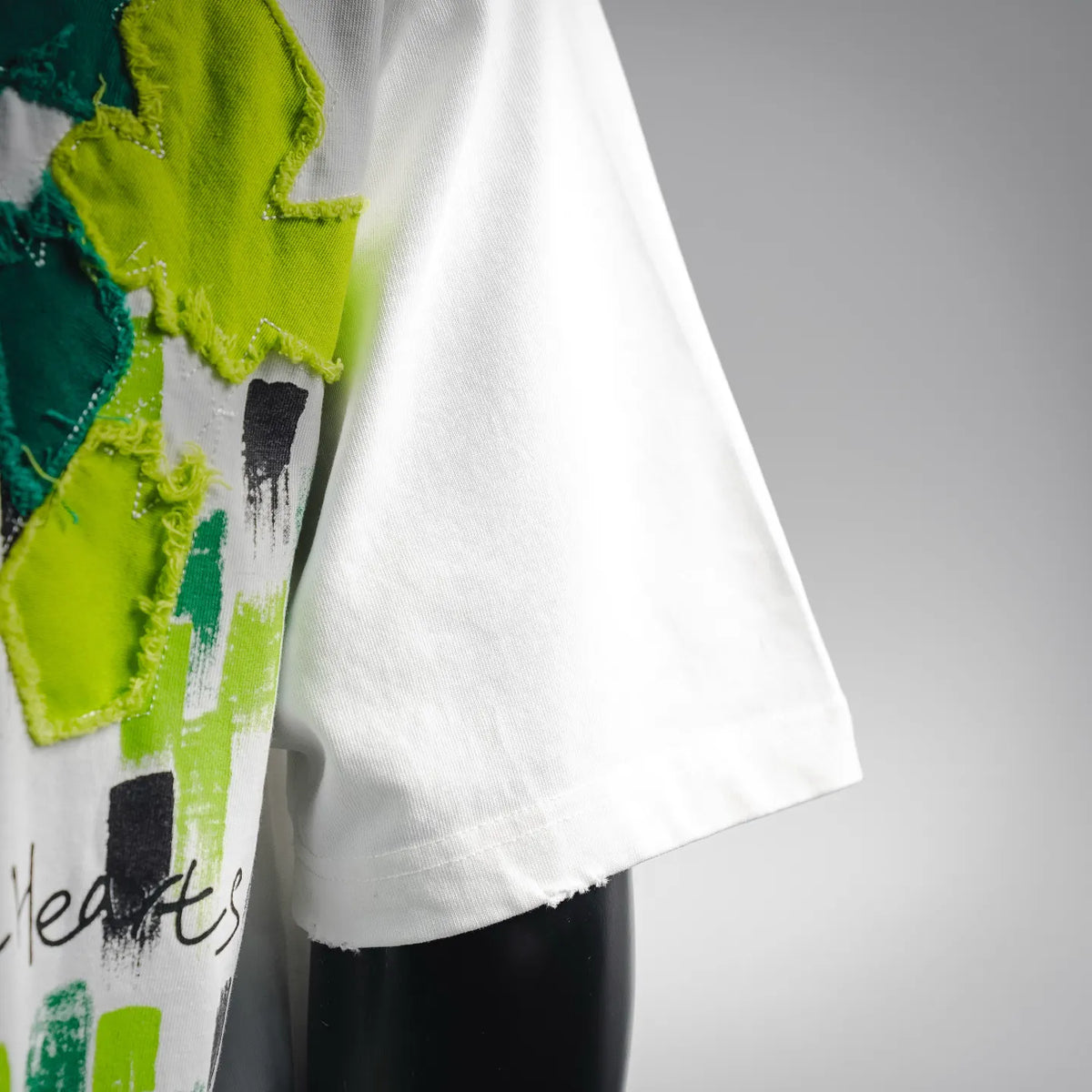 White short-sleeve T-shirt with green embroidered flower applique and straight hem