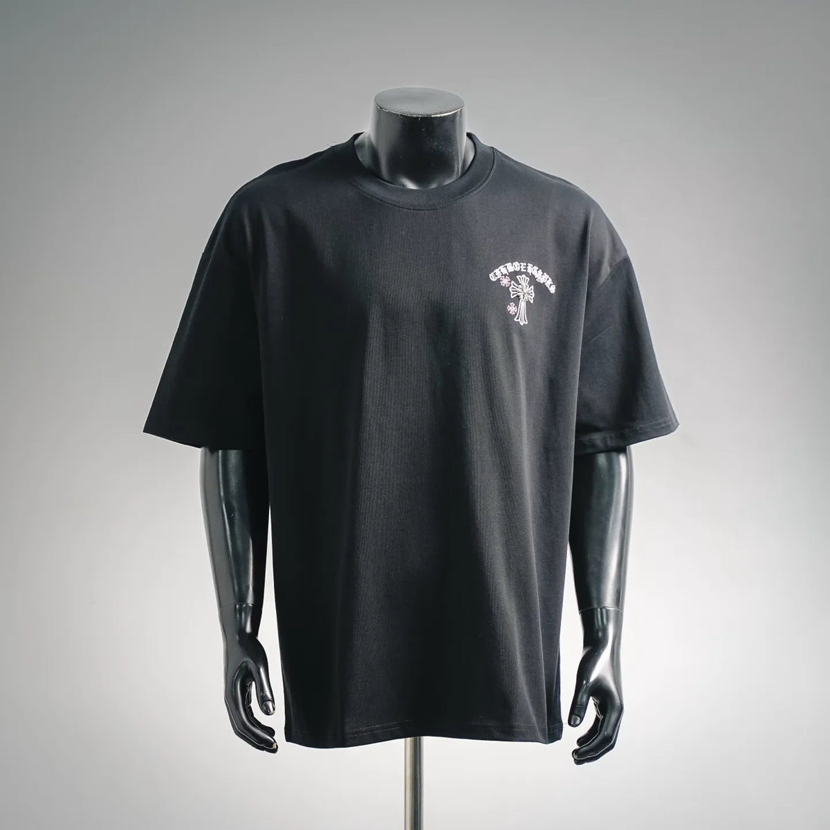 Black short-sleeve T-shirt on mannequin with small white chest cross embroidery.