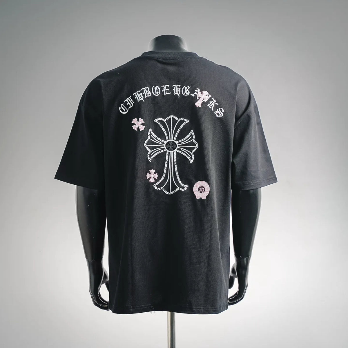 Black short-sleeve T-shirt with large white cross graphic on back, pink accents.