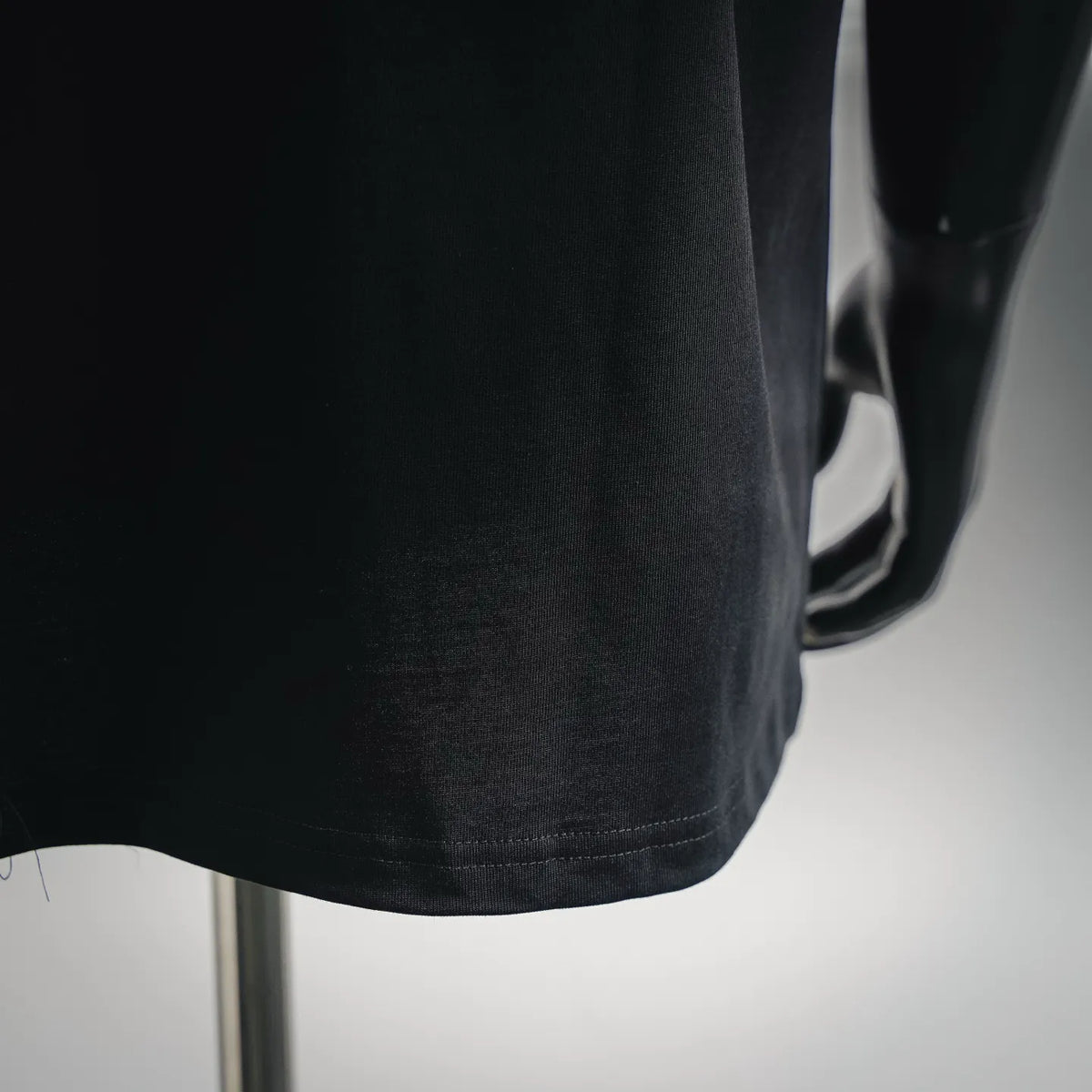 Black T-shirt hem and side seam detail with smooth knit finish.