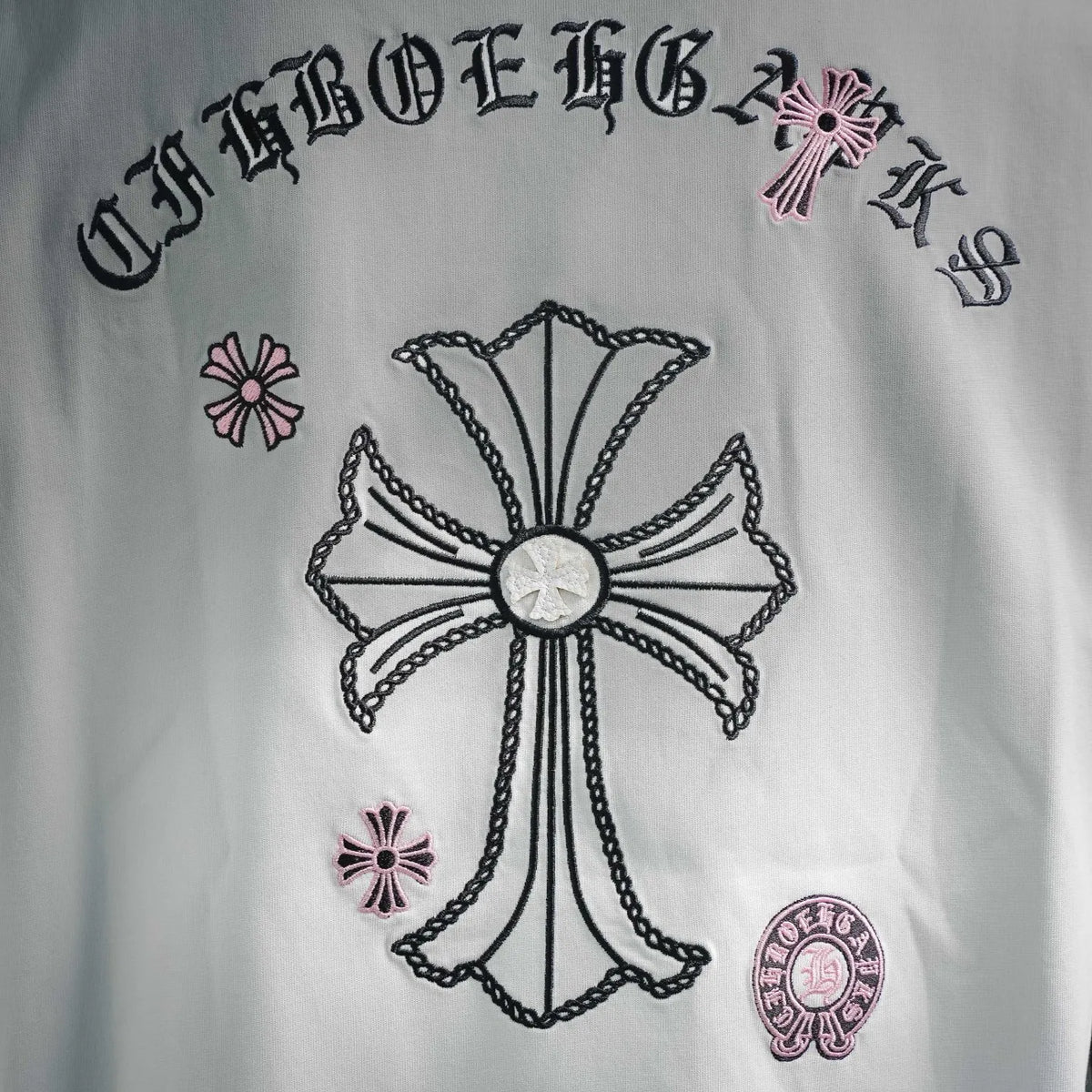 White T-shirt back graphic close-up: cross design with text arc and small icons