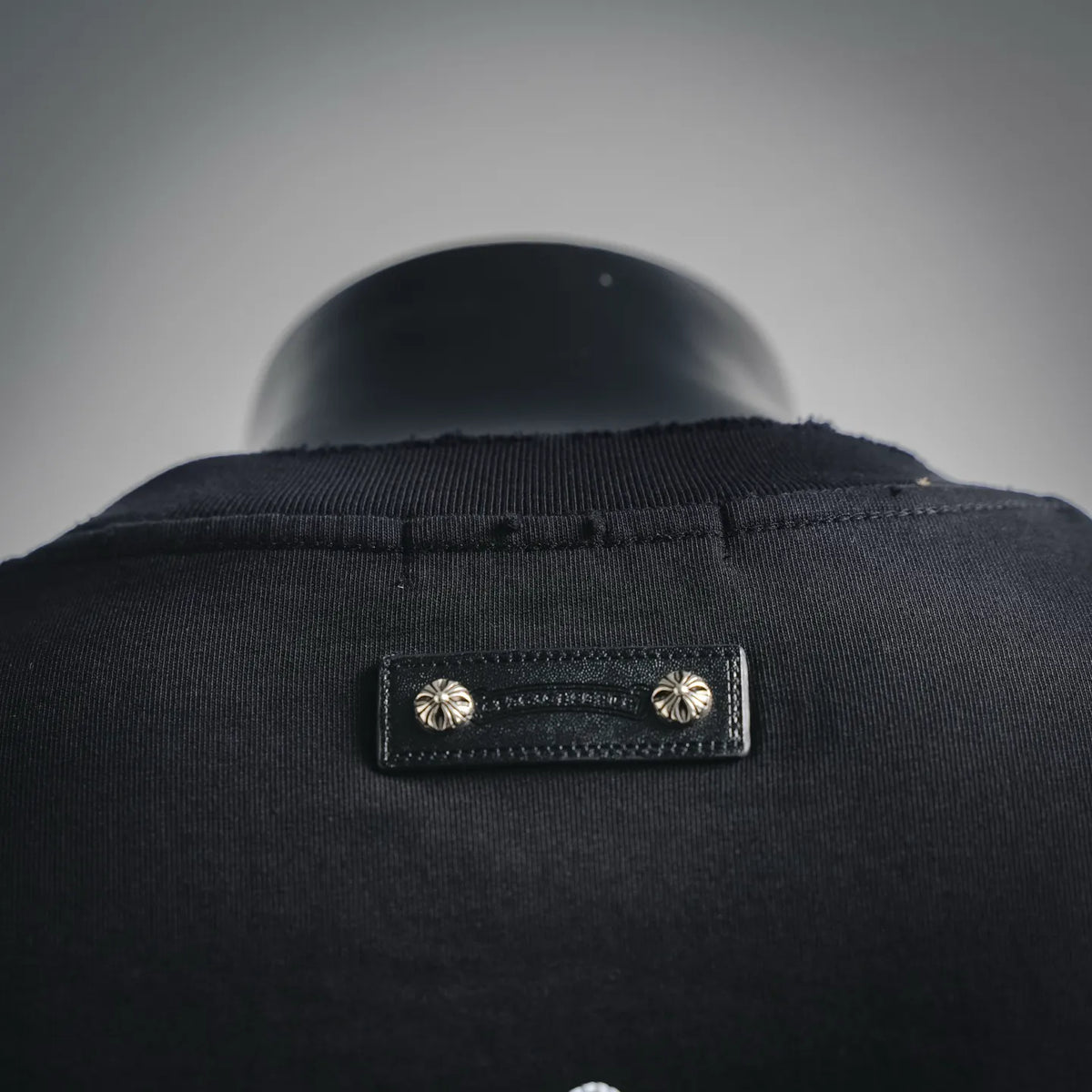 Black T-shirt neckline with stitched label and small metal button accents