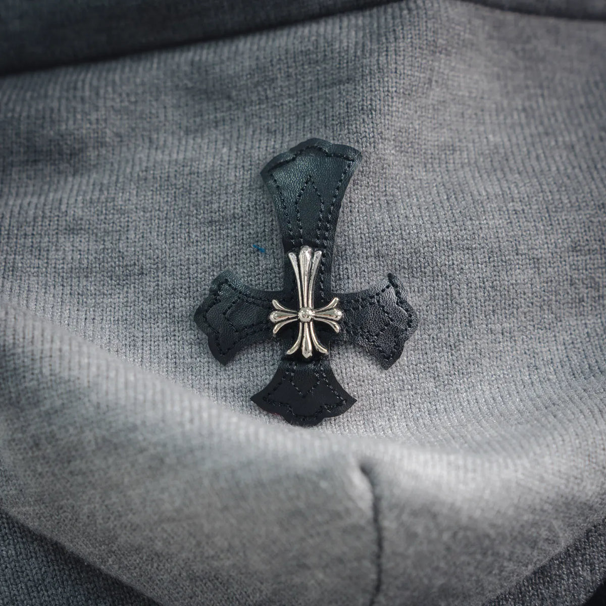 Light gray hoodie with dark cross graphic applique and small jeweled accents.