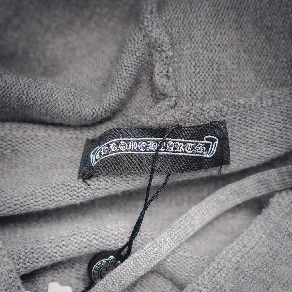 Light gray hoodie neck label with black brand tag and drawcord.