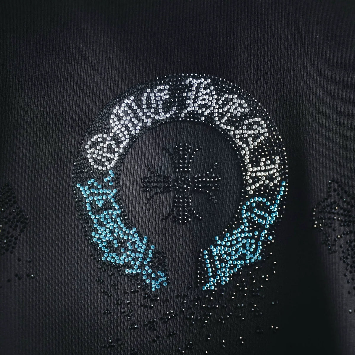 Black T-shirt close-up: silver and blue rhinestone circular face with star accents