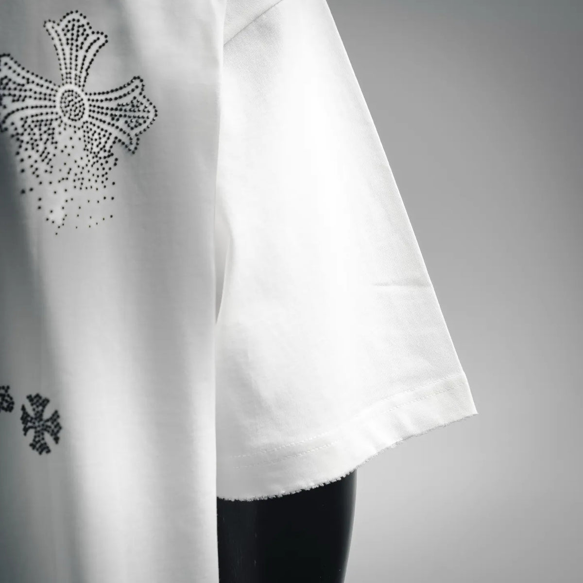 White T-shirt side view with stitched hem and partial rhinestone graphic