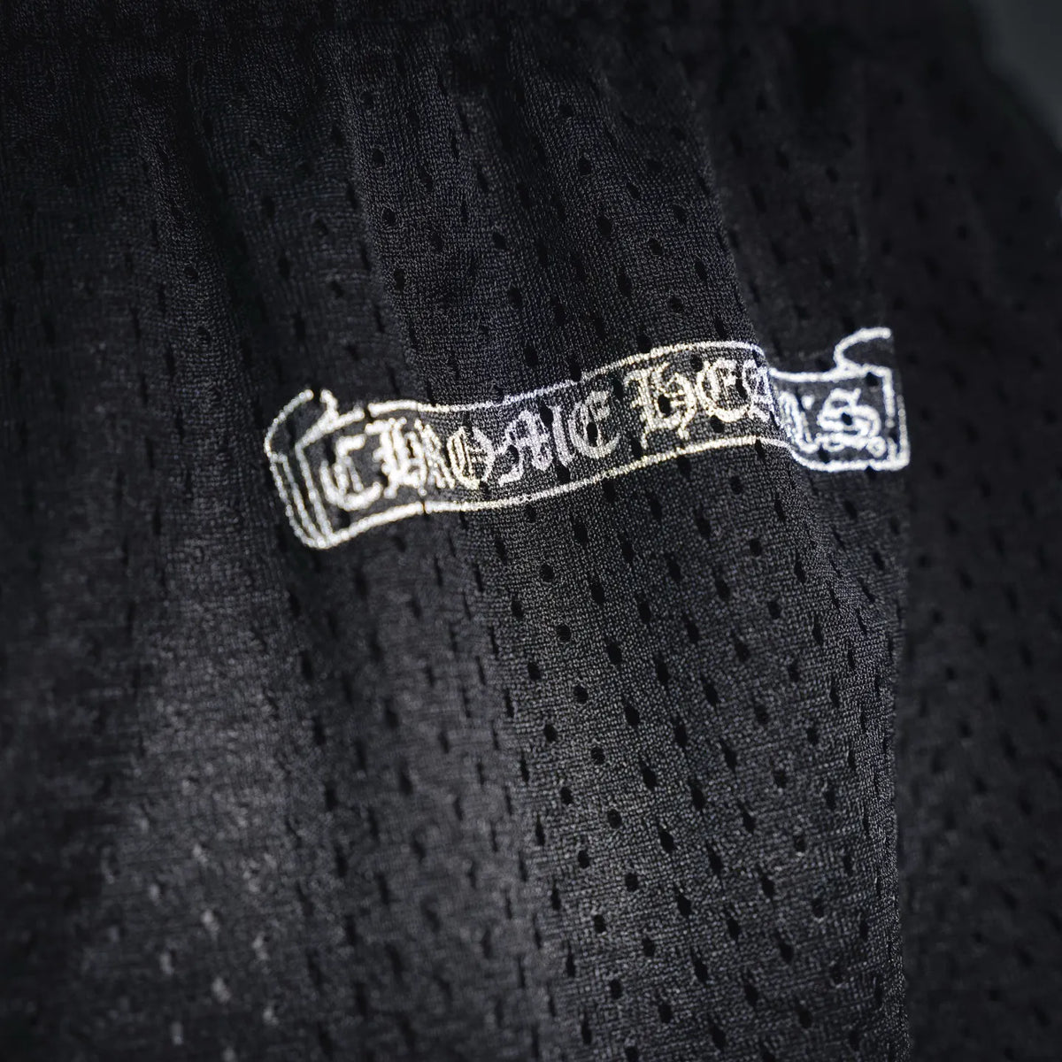Black chrome pants fabric detail with white logo patch