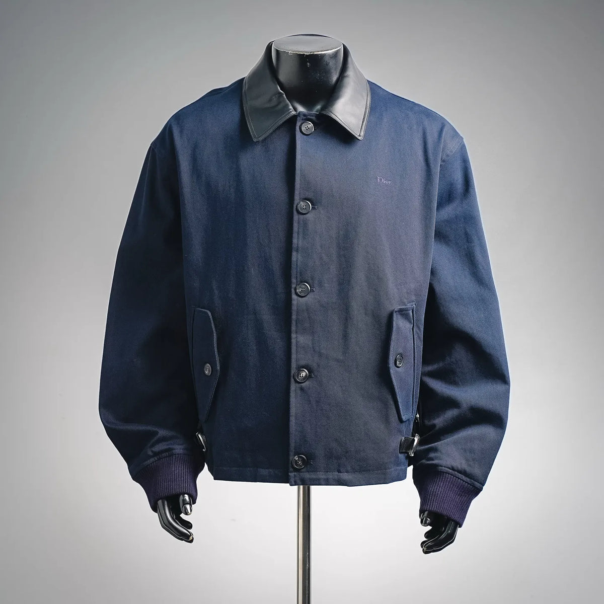 Navy denim coat with button front, flap pockets, and black leather-look collar