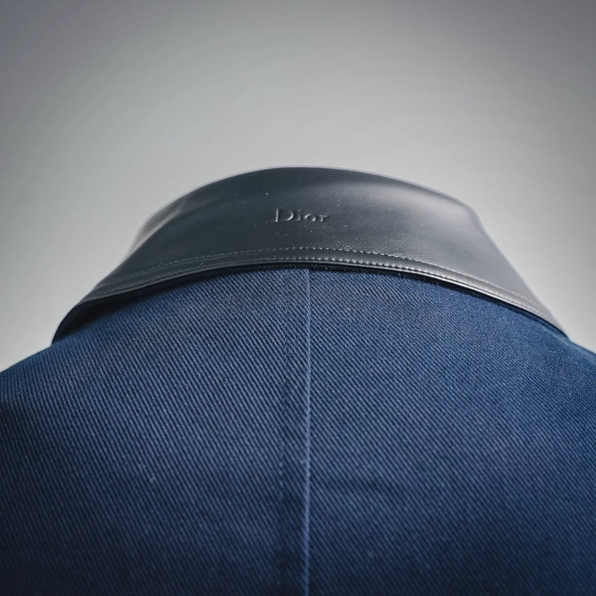 Navy denim coat with black leather yoke and Dior stamp at upper back