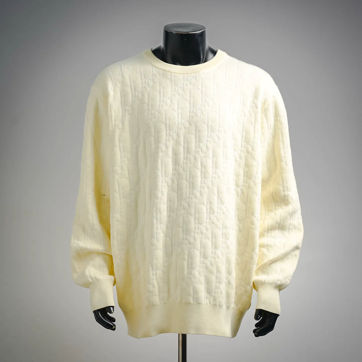 Cream knit sweater with crew neck and ribbed cuffs on a mannequin