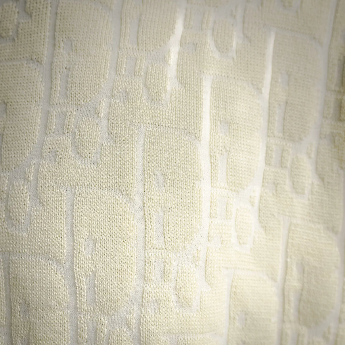 Close-up of cream knit sweater fabric texture with vertical raised details