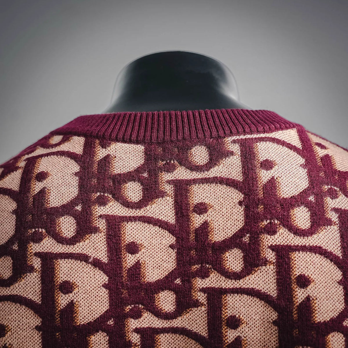 Burgundy knit sweater collar and shoulders with repeating beige monogram pattern