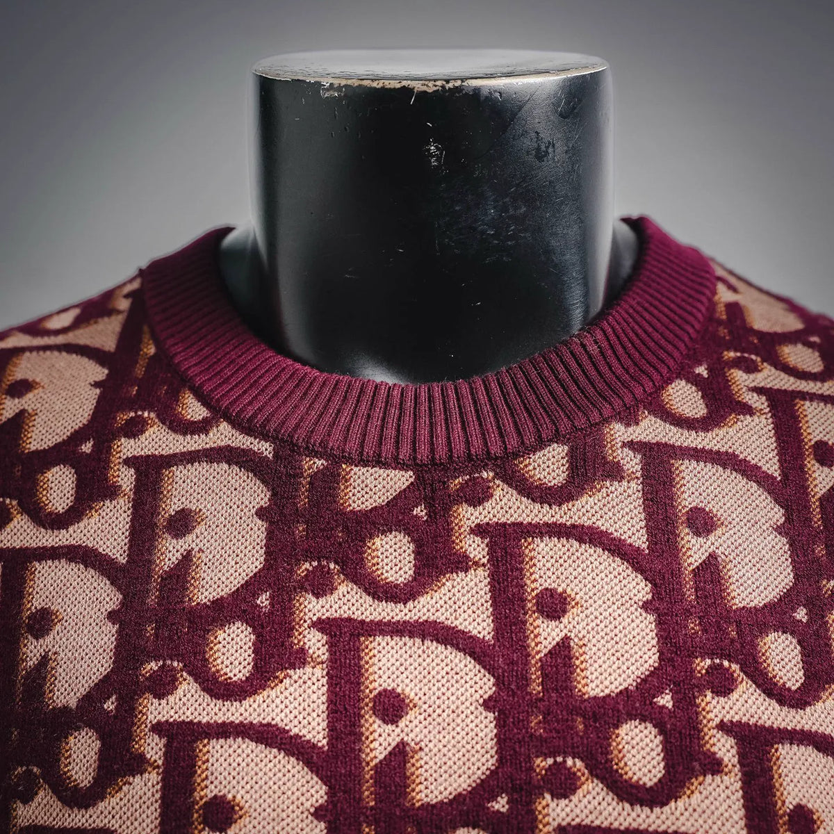 Ribbed crew neckline on burgundy knit sweater with beige monogram pattern