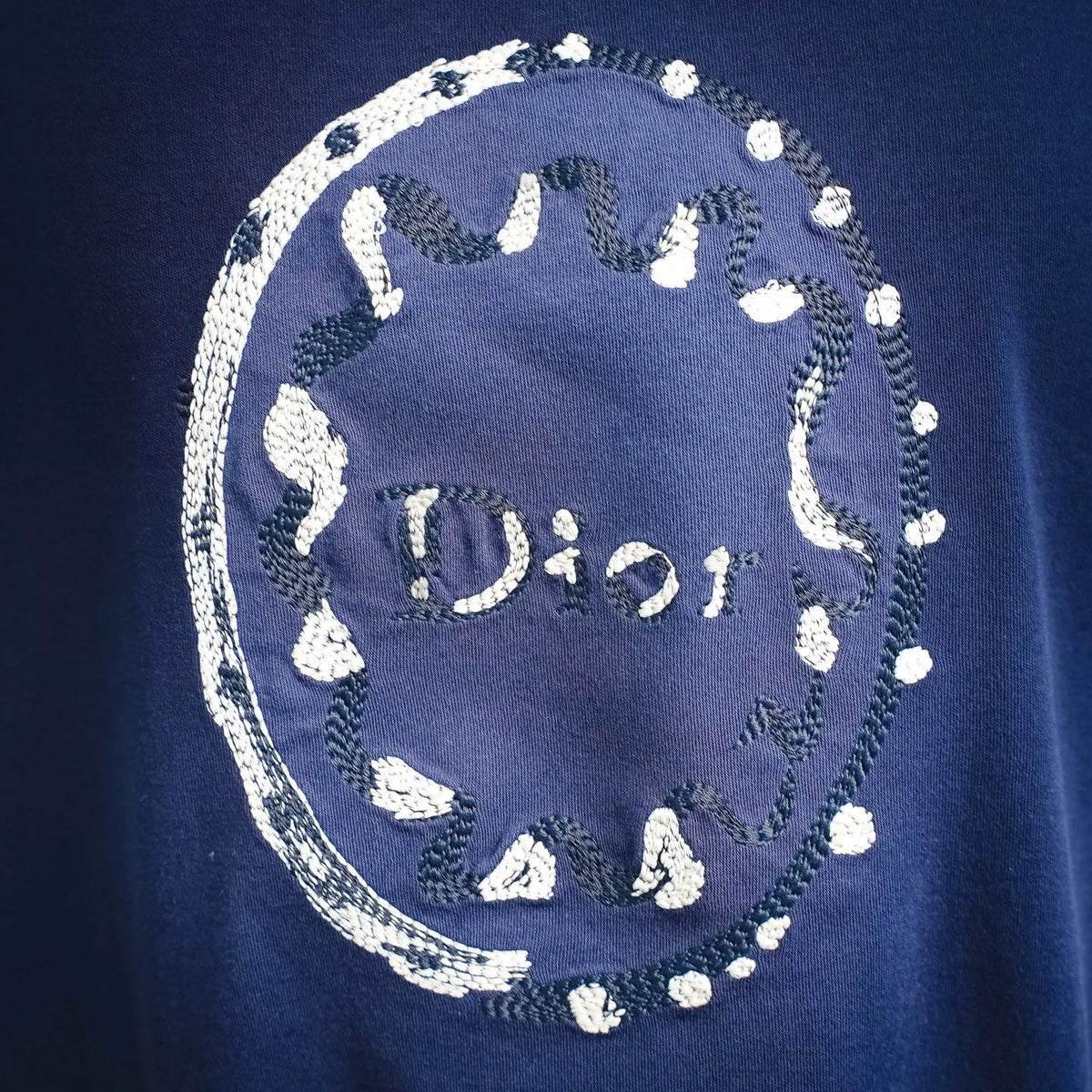 Blue Dior T-shirt close-up: circular white logo graphic