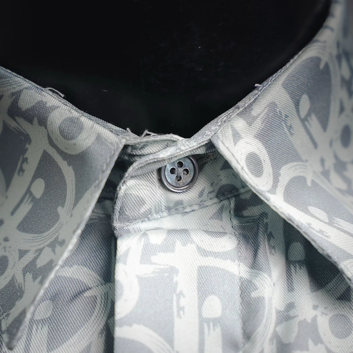 Close-up of button placket at the collar on a light blue and white monogram shirt