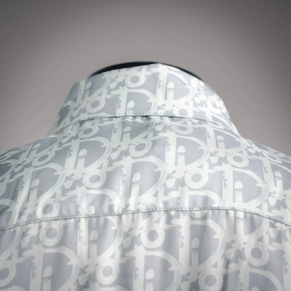 Stand collar of a light blue and white monogram button-up shirt with stitched edge